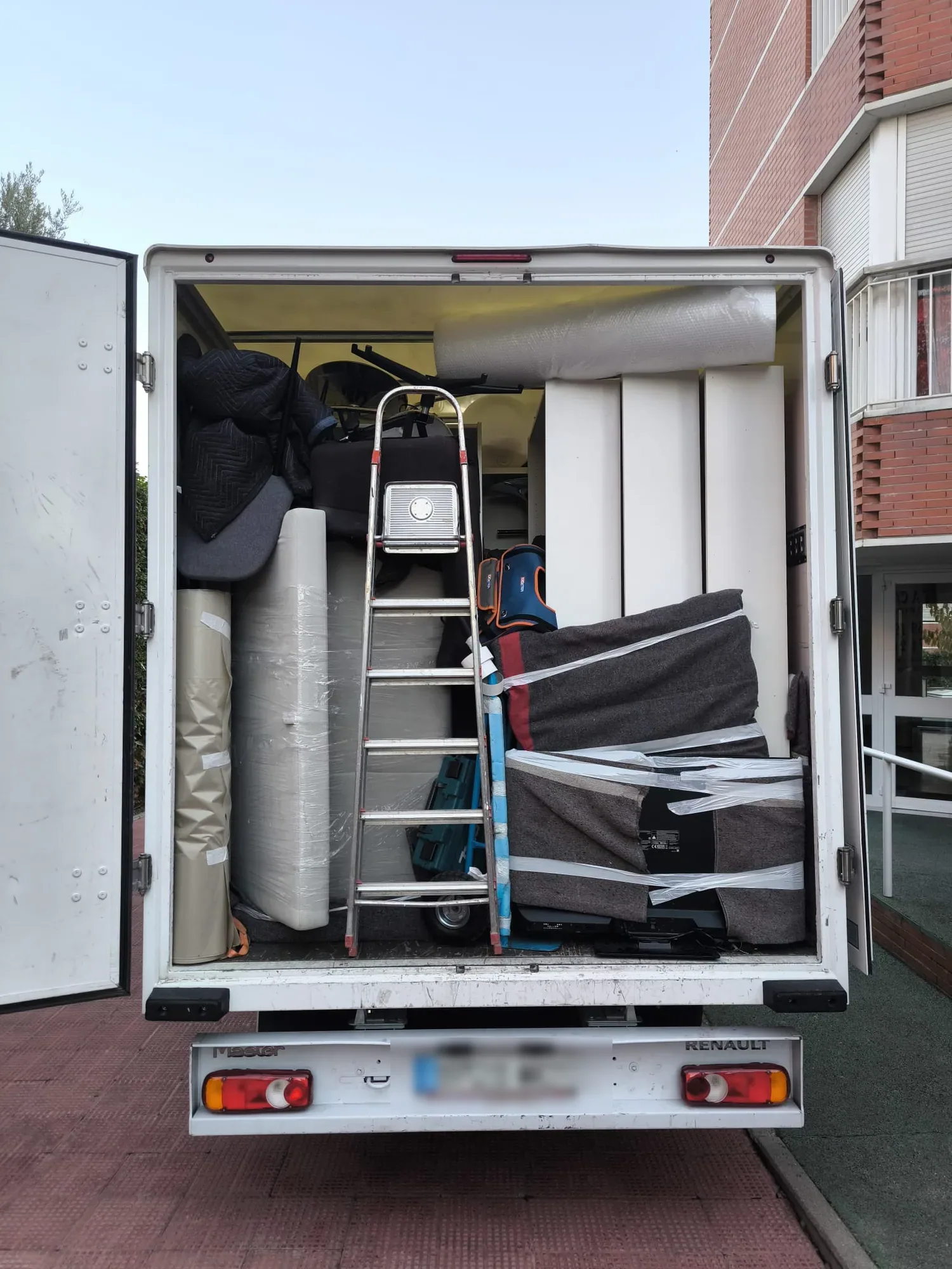 Camión cargado con colchones, mantas y escalera para una mudanza